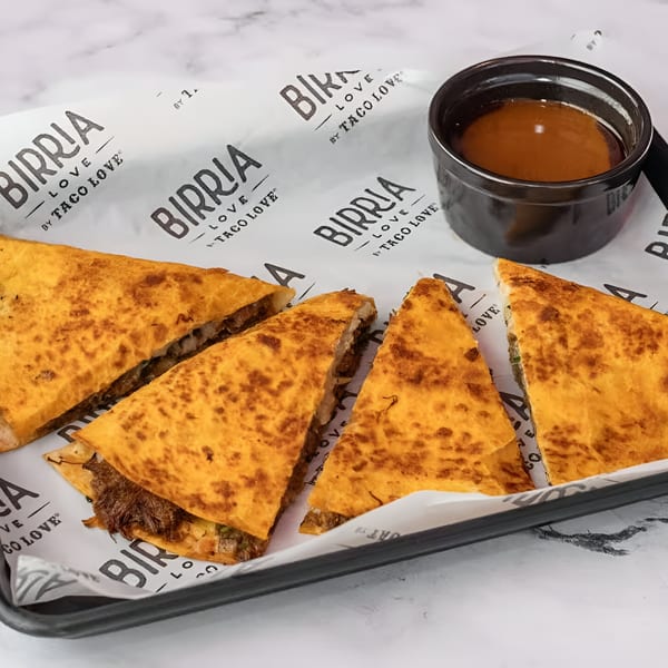 Birria Love quesadillas with shredded meat and cheese, served with a side of dipping sauce.