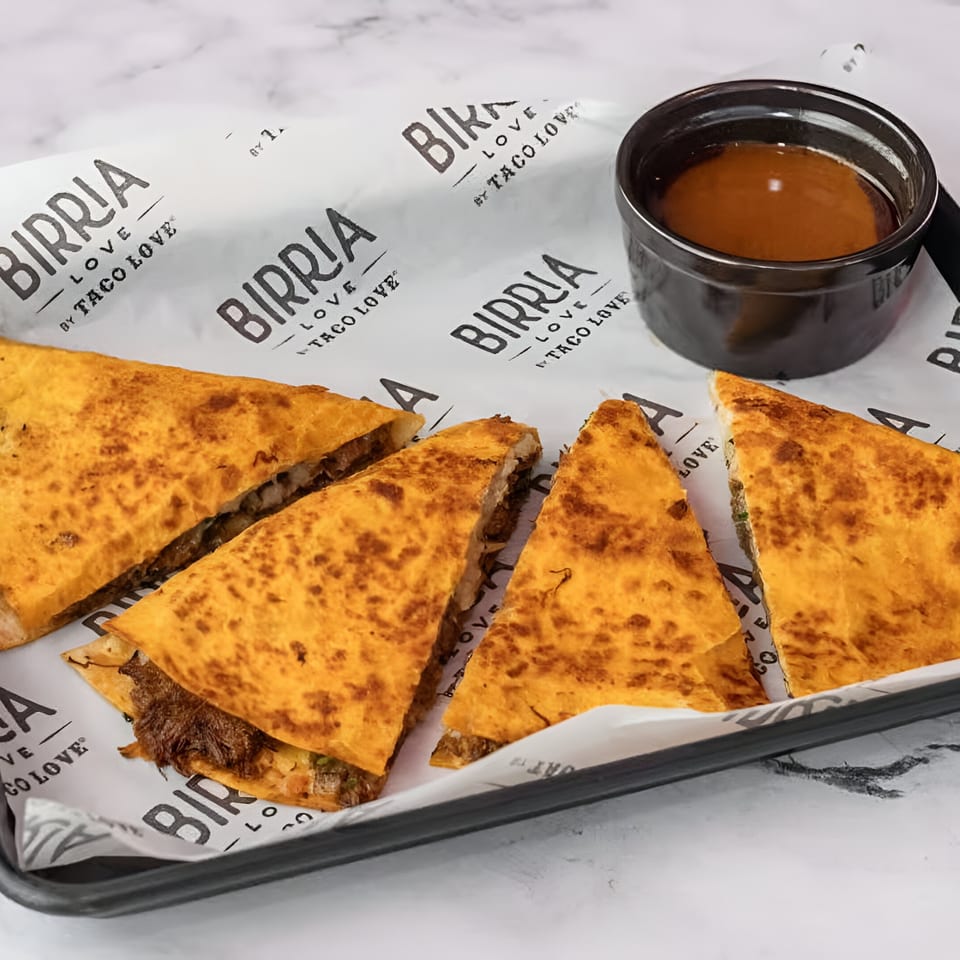 Birria Love quesadillas with shredded meat and cheese, served with a side of dipping sauce.